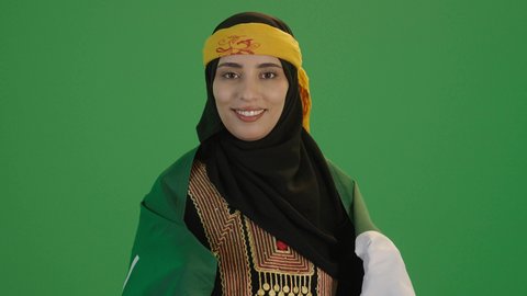 ذكرى تأسيس الدولة السعودية الأولى 22 فبراير, ارتداء أزياء المنطقة الوسطى، بورتريه لإمرأة عربية خليجية سعودية مبتسمة ترتدي الكرتة والهامة وتنظر إلى الكاميرا بايماءات السعادة والسرور, الاحتفال بالمناسبات والأعياد الوطنية الشعبية، خلفية خضراء، كروما