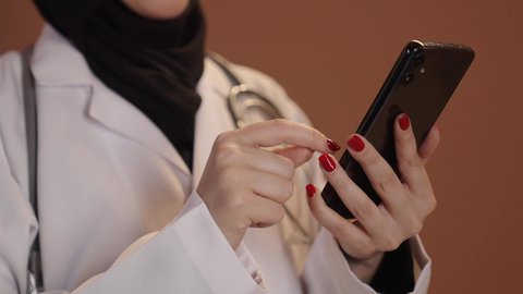 استخدام الجوال في البحث والتطوير، بورتريه مقرب ليد لطبيبة عربية خليجية سعودية محجبة ترتدي المعطف الابيض وتضع سماعتها الطبية حول رقبتها، تقديم الخدمات للمرضى بكل كفاءه, إجراء الاستشارت الطبية والخدمات العلاجية للمرضى عبر الأونلاين, خلفيه بنية