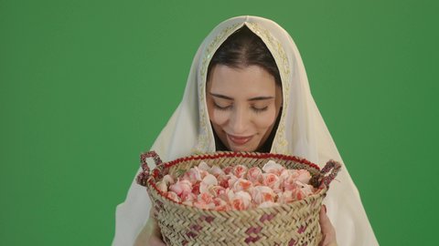 الزي السعودي التقليدي الشعبي, المناسبات والأعياد الوطنية، ذكرى تأسيس الدولة السعودية الاولى 22 فبراير، بورتريه لشابة عربية خليجية سعودية ترتدي الثوب الابيض المطرز بالذهبي وتضع الشيله على رأسها تحمل بيدها سلة من القش ممتلئة بالورد الجوري الطبيعي، ، خلفية خضراء, كروما