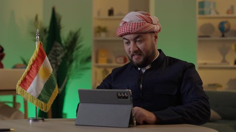 إدارة شؤون الأعمال وتنظيمها عبر الاجهزة التقنية، دمج العمل مع التقنية والتكنولوجيا، تصفح مواقع التواصل الاجتماعي، رجل اعمال عربي خليجي سعودي يرتدي الزي التقليدي والشماغ  يعمل على جهاز التابلت بإيماءات التركيز، موظف سعودي يعمل على جهاز اللابتوب