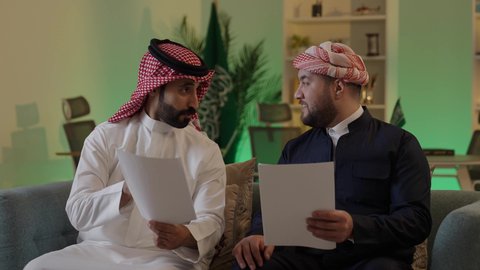 التفاهم والتعاون بين الزملاء لتحقيق أهداف الشركة، التحقق والتدقيق في العروض المالية، تطوير خطة وآلية العمل، رجل عربي خليجي سعودي يرتدي الزي التقليدي والشماغ يقوم بشرح المهام لزميله، كتابة وتسجيل الملاحظات, إنجاز الأعمال المكتبية