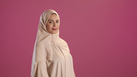 الأناقة و الاهتمام بالمظهر الخارجي, مفهوم الأنوثة و النعومة, بورتريه لامرأة عربية خليجية سعودية ترتدي العباءة والحجاب تنظر الى الكاميرا بايماءات السعادة ، تعابير البهجة والسرور، خلفية حمراء