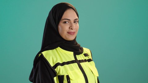 The concept of engineering project management, women's jobs and professions, a portrait of an Arab Gulf Emirati female architect wearing a helmet and safety vest standing with expressions of joy and happiness, a young Saudi woman looking at the camera with gestures of delight working in the engineering sector, chroma, green background.
