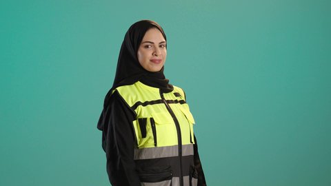 وظائف ومهن نسائية, مفهوم ادارة المشاريع الهندسية, بورتريه لمهندسة معمارية عربية خليجية امارتية ترتدي خوذة وسترة الحماية تقف بتعابير البهجة والسعادة، شابة سعودية تنظر الكاميرا بايماءات السرور تعمل في القطاع الهندسي، كروما ، خلفية خضراء