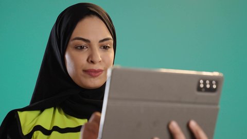 Integrating modern technologies in engineering, studying the fundamentals of the project, working in the engineering sector, managing engineering projects, a portrait of an Arab Gulf Emirati engineer wearing a vest and safety helmet working on a tablet, a young Saudi woman supervising the work, chroma, green background.