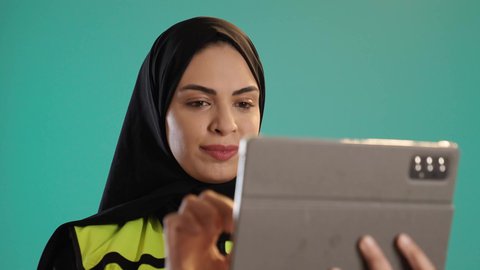 Study the fundamentals of the project, integrating modern technologies in engineering, working in the engineering sector, managing engineering projects, a portrait of an Emirati Gulf Arab engineer wearing a vest and safety helmet working on a tablet, a young Saudi woman supervising the work, chroma, green background.