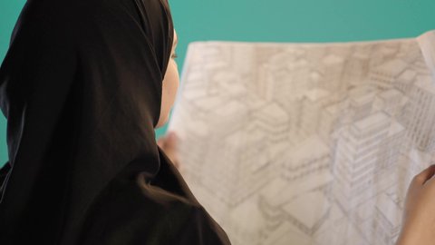 بورتريه لامرأة عربية خليجية اماراتية ترتدي الحجاب وخوذة وسترة الحماية تحمل بيدها مخطط المشروع، شابة سعودية تقوم بالاشراف على العمل، مهن ووظائف نسائية، المخططات و المشاريع الاعمارية، العمل في القطاع الهندسي، كروما ، خلفية خضراء