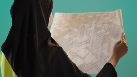 المخططات و المشاريع الاعمارية، مهن ووظائف نسائية،العمل في القطاع الهندسي، بورتريه لامرأة عربية خليجية اماراتية ترتدي الحجاب وخوذة وسترة الحماية تحمل بيدها مخطط المشروع، شابة سعودية تقوم بالاشراف على العمل، كروما ، خلفية خضراء