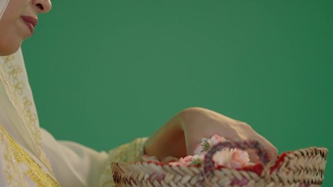 ذكرى تأسيس الدولة السعودية الاولى 22 فبراير، المناسبات والأعياد الوطنية، بورتريه لشابة عربية خليجية سعودية ترتدي الثوب الابيض المطرز بالذهبي وتضع الشيله على رأسها تحمل بيدها سلة من القش ممتلئة بالورد الجوري الطبيعي، الزي السعودي التقليدي الشعبي ، كروما ، خلفية خضراء