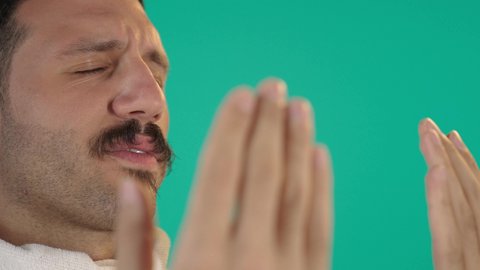 الدعاء و التضرع لرب العباد, مفهوم أركان الإسلام، اداء مناسك الحج والعمرة، العبادة والتقرب الى الله، رجل عربي خليجي سعودي يرتدي لباس الاحرام يرفع يديه بايماءات الدعاء ،الطاعة والتقرب الى الله، خلفية خضراء ، كروما