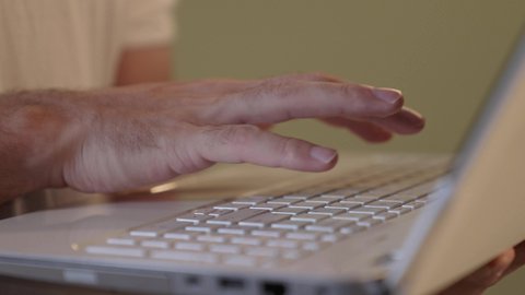 تصفح مواقع التواصل الاجتماعي، إدارة شؤون العمل وتنظيمه، رجل عربي خليجي سعودي يرتدي  السروال والفانيله البيضاء يقوم بالعمل على الحاسوب المحمول بإيماءات التركيز، استخدام التقنيات الحديثة المتطورة