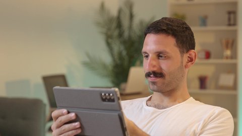 دمج التكنولوجيا والتقنيات الحديثة فى الحياه اليوميه ، استخدام تطبيقات وبرامج الأجهزة اللوحية، الدردشة مع الأهل والأصدقاء، رجل عربي خليجي سعودي يرتدي السروال والفانيله البيضاء  يحمل بيده جهاز التابلت، تصفح مواقع التواصل الاجتماعي