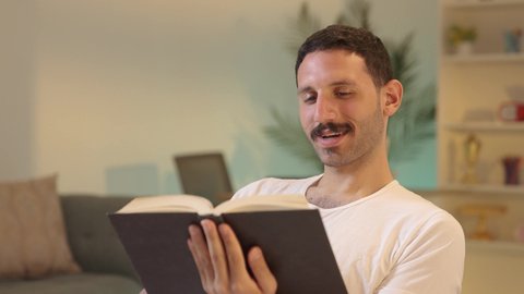 الأنشطة الترفيهية المفيدة, الاستمتاع بممارسة هواية المطالعة، رجل عربي خليجي سعودي يرتدي السروال والفانيله البيضاء يمسك بيده كتاب  ، الروايات والكتب التثقيفية