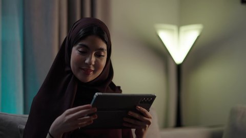 امراه عربيه خليجيه عمانيه ترتدي العباءه والحجاب تحمل بيدها جهاز التابلت، تصفح مواقع التواصل الاجتماعي، استخدام تطبيقات وبرامج الأجهزة اللوحية، الدردشة مع الأهل والأصدقاء، دمج التكنولوجيا والتقنيات الحديثة فى الحياه اليوميه
