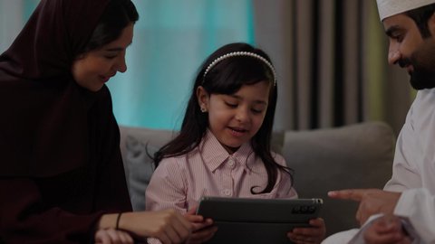 تصفح مواقع التواصل الاجتماعي، استخدام تطبيقات وبرامج الأجهزة اللوحية، الدردشة مع الأهل والأصدقاء، دمج التكنولوجيا والتقنيات الحديثة فى الحياه اليوميه ، مفهوم المحبة والمودة، الجلوس في غرفة المعيشة في جو عائلي ، بورتريه لعائلة عربية خليجية عمانية ترتدي الأزياء التقليدية