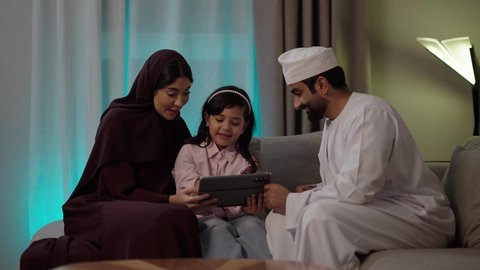 الدردشة مع الأهل والأصدقاء، استخدام تطبيقات وبرامج الأجهزة اللوحية،دمج التكنولوجيا والتقنيات الحديثة فى الحياه اليوميه ، مفهوم المحبة والمودة، الجلوس في غرفة المعيشة في جو عائلي ، بورتريه لعائلة عربية خليجية عمانية ترتدي الأزياء التقليدية ، تصفح مواقع التواصل الاجتماعي