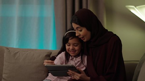 مفهوم المحبة والمودة، الجلوس في غرفة المعيشة في جو عائلي ، استخدام تطبيقات وبرامج الأجهزة اللوحية، الدردشة مع الأهل والأصدقاء، دمج التكنولوجيا والتقنيات الحديثة فى الحياه اليوميه ،بورتريه لعائلة عربية خليجية عمانية ترتدي الأزياء التقليدية ، تصفح مواقع التواصل الاجتماعي