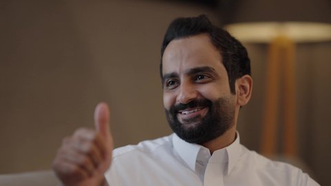 توثيق اللحظات السعيدة ، تعابير الموافقة و القبول، الأجواء العائلية السعيدة، تقوية العلاقات الزوجية وروابط الحب والمودة، التقاط صور السيلفي التذكارية باستخدام الهاتف المحمول، زوجان عربيان خليجيان سعوديان يرتديان الزي التقليدي يجلسان فى غرفه المعيشة يستخدمان الجوال