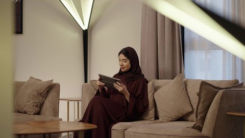 التعبير عن الألفة والمحبة بين الزوجين، إحياء ذكرى يوم الزواج، تصفح الانترنت ومواقع التواصل الاجتماعي عبر جهاز التابلت, رجل عربي خليجي سعودي يرتدى الثوب الابيض يقدم لزوجته هديه في علبه بمناسبة عيد الحب, إيماءات السعادة والسرور