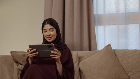 إحياء ذكرى يوم الزواج، تصفح الانترنت ومواقع التواصل الاجتماعي عبر جهاز التابلت, رجل عربي خليجي سعودي يرتدى الثوب الابيض يقدم لزوجته هديه في علبه بمناسبة عيد الحب،  التعبير عن الألفة والمحبة بين الزوجين, إيماءات السعادة والسرور