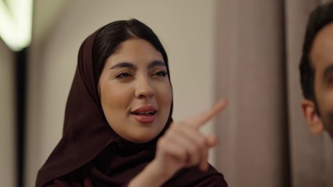 تعابير السلام و التحية، التقاط صور التذكارية عبر الجوال، الأجواء العائلية السعيدة، توثيق اللحظات السعيدة ، تقوية العلاقات الزوجية وروابط الحب والمودة، زوجان عربيان خليجيان سعوديان يرتديان الزي التقليدي يجلسان فى غرفه المعيشة