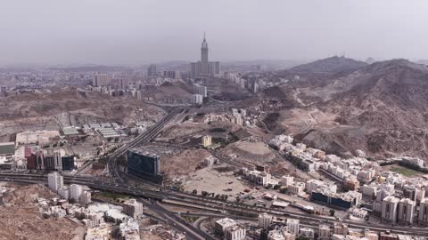 الأفق والأبراج وناطحات السحاب في وقت النهار، التشكيل والتكوين الصخري للمرتفع الجبلي في مكة المكرمة، تصوير درون جوي لحركة سير السيارات على ممر جبلي ملتوي، الأجواء الضبابية على الجبل في المملكة العربية السعودية،  الفن الهندسي المعماري لمعالم دينية إسلامية مقدسة