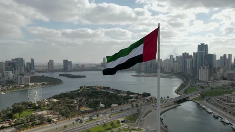 الإعتزاز والفخر بالهوية الوطنية، حب الوطن والانتماء اليه، الإحتفال باليوم الوطني الإماراتي، عرض طائرة بدون طيار لعلم الإمارات العربية المتحدة يرفرف في الهواء في يوم غائم، الرمز الوطني لدولة الإمارات العربية المتحدة فوق جزيرة علم الشارقة، الإمارات العربية المتحدة