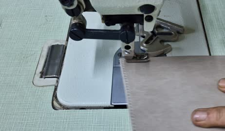 مهن وحرف يدوية, فن اتقان مهنة الخياطة, أدوات ومعدات تفصيل أقمشة الأثاث, معامل ومصانع في الامارات العربية المتحدة, تصوير مقرب ليد خياط عربي خليجي اماراتي يستخدم الماكينة لحياكة وصناعة جلود الكراسي والكنب، مهن ووظائف يدوية