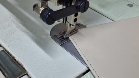 Crafts and manual professions, the art of mastering the sewing profession, tools and equipment for tailoring upholstery fabrics, workshops and factories in the United Arab Emirates, close-up shot of an Emirati Gulf Arab tailor's hand using a machine to sew and manufacture chair and sofa upholstery, manual professions and jobs.