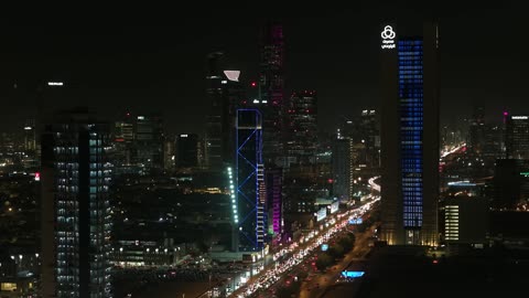 النمو والتطور العمراني في المملكة العربية السعودية، تصوير درون للفن الهندسي المعماري لمدينة الرياض في وقت الليل، الأبراج وناطحات السحاب والمنشآت والمباني التجارية، التقدم الحضاري في المدن والأحياء، برج المملكة الشامخ المضيء ليلا، أماكن سياحية مشهورة