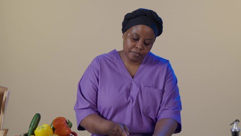 إعداد وتجهيز الوجبات اليومية، غذاء مفيد وصحي، بورتريه لعاملة فلبينية ترتدي اليونيفورم الخاص تقف في المطبخ تقوم بتقطيع الخضار, مفهوم النظام الغذائي، وصفات الطعام الشهية، خلفية بنية