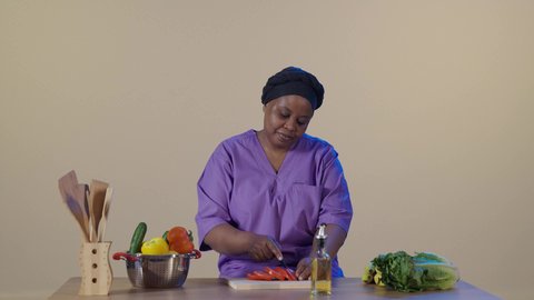 Preparation and preparation of the necessary ingredients, preparing vegetables in the kitchen, a foreign worker wearing the special uniform is cutting vegetables alongside the housewife, employing licensed and qualified workers from Saudi companies and offices, gestures of thanks and gratitude for the quality of service and performance of the domestic worker.