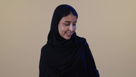 مفهوم التنظيف والإهتمام بالمسؤوليات المنزلية، إزالة البقع والأوساخ من الأطباق، أداء مهام المطبخ, بورتريه لامراه عربيه خليجيه سعودية محجبة ترتدي العباءة و القفازات تقوم بغسيل الأطباق باستخدام اسفنجة الجلي