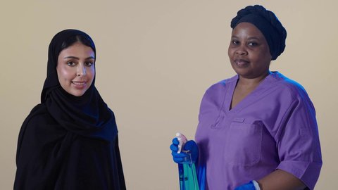 توفير خدمات العناية بالمنزل والنظافة والترتيب، ايماءات السعادة والرضا عن جودة خدمة العاملة، سيدة عربية خليجية سعودية  تقف برفقة خادمة فلبينية تمسك بيديها ادوات النظافة، استقدام العمالة الخارجية المرخصة والمؤهلة