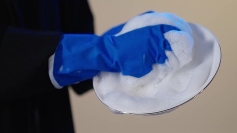 أداء مهام المطبخ, بورترية مقرب ليد امراه عربيه خليجيه سعودية ترتدي القفازات تقوم بغسيل الأطباق باستخدام اسفنجة الجلي، إزالة البقع والأوساخ من الأطباق، مفهوم التنظيف والإهتمام بالمسؤوليات المنزلية