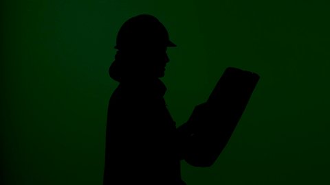 التصاميم المعمارية وتدقيق المخططات , تصوير ظلى لمهندسة عربية خليجية سعودية ترتدي سترة الحماية و الخوذة  تمسك بيدها مخططات هندسية وتقف بإيماءات الثقة والفخر, التدقيق والإشراف على المشاريع الهندسية في موقع العمل