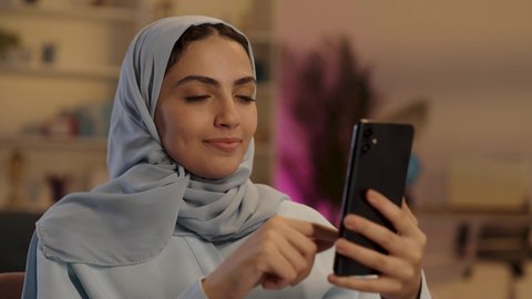 قضاء وقت ممتع عبر الجوال مع الأصحاب، امرأة عربية خليجية سعودية محجبة ترتدي العباءة الرمادية تقوم بإستخدام الهاتف المحمول، استخدام التكنولوجيا والتقنية الحديثة