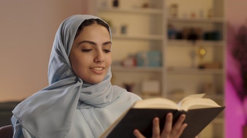 تمضية وقت الفراغ بالتعلم والتثقيف الذاتي, امرأة عربية خليجية سعودية ترتدي العباءة الرمادية والحجاب تحمل بيدها كتاب تثقيفي,  إيماءات التركيز والاندماج