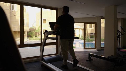 المحافظة على الصحة واللياقة البدنية, استخدام الاجهزة الرياضية، ممارسة تمارين الاحماء,  شاب عربي خليجي سعودي يرتدي الملابس الرياضية يقوم بالمشي على الجهاز الكهربائي، نادي الألعاب الرياضية, القيام بالأنشطة الترفيهية الممتعة