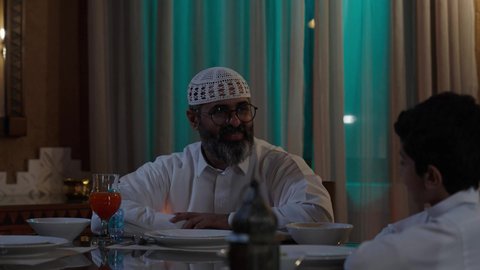 تجهيز طاولة الطعام قبل الاذان, أداء فريضة الصيام في شهر رمضان المبارك، قضاء أوقات ممتعه مع الأهل والأبناء، تبادل الأحاديث بين أفراد الأسرة، طفل عربي خليجي سعودي مجتمع مع عائلته حول مائدة الطعام، سفرة مليئة بأصناف من المأكولات الشرقية الشهية