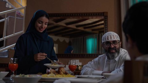 سكب وتوزيع الطعام من قبل الام لباقي افراد الأسرة,  أداء فريضة الصيام في شهر رمضان المبارك، قضاء أوقات ممتعه مع الأهل والأبناء، تبادل الأحاديث بين أفراد الأسرة، طفل عربي خليجي سعودي مجتمع مع عائلته حول مائدة الطعام، سفرة مليئة بأصناف من المأكولات الشرقية الشهية
