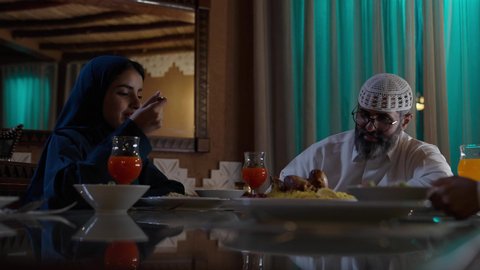 تبادل الأحاديث والاخبار, أداء فريضة الصيام في شهر رمضان المبارك، قضاء أوقات ممتعه مع الأهل والأبناء، تبادل الأحاديث بين أفراد الأسرة، طفل عربي خليجي سعودي مجتمع مع عائلته حول مائدة الطعام، سفرة مليئة بأصناف من المأكولات الشرقية الشهية