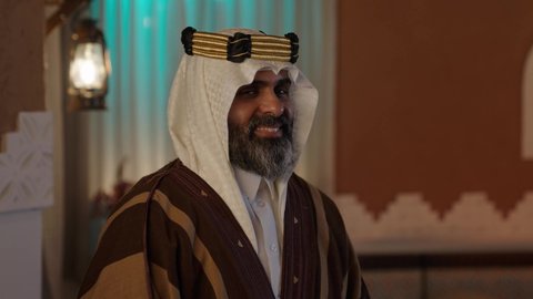 بيوت تراثيه قديمه, النظر للكاميرا بايماءات السرور، أزياء سعودية تقليدية شعبية، تصوير لرجل مسن عربي سعودي خليجي يرتدي الزي السعودي الشعبي التقليدي, الزي التراثي للمناسبات الوطنيه, التجول داخل منزل تراثي بتصميم عصري, شعبيات, أحياء أثريه قديمه