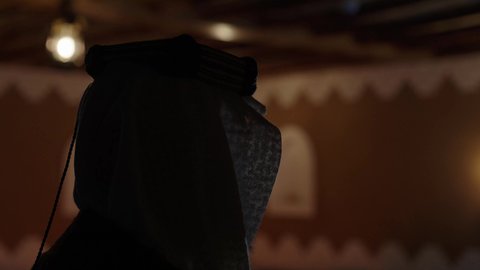 تصوير من الخلف لرجل مسن عربي سعودي خليجي يرتدي الزي السعودي الشعبي التقليدي, الزي التراثي للمناسبات الوطنيه, التجول داخل منزل تراثي بتصميم عصري, بيوت تراثيه قديمه, شعبيات, أحياء أثريه قديمه, جوله بين الأحياء الشعبيه، أزياء سعودية تقليدية شعبية