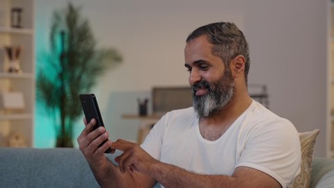 تعابير السعادة و السرور، دمج التقنية والتكنولوجيا في الحياة اليومية، تصوير مقرب لرجل عربي خليجي سعودي يرتدي السروال والفانيله البيضاء يحمل بيده الهاتف المحمول, دمج التقنية والتكنولوجيا في الحياة اليومية