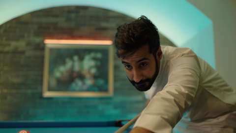 أنشطه وهوايات شبابيه، صاله رياضيه شبابيه، مفهوم المنافسات والتحديات، قضاء أوقات الفراغ ممتعه, طاولة بلياردو (السنوكر), شاب عربي خليجي سعودي يرتدي الثوب الابيض يقومب بممارسة لعبة البلياردو