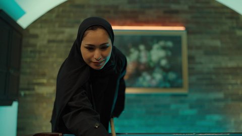 أنشطه وهوايات شبابيه, قضاء وقت ممتع فى الخارج، تصوير لامراه عربيه خليجيه سعودية محجبه ترتدي العباءة السوداء تقوم بممارسة لعبة البلياردو، صاله رياضيه شبابيه