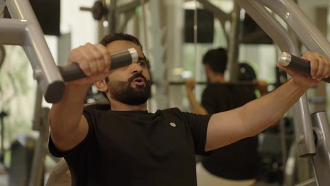 أسلوب حياة صحي، إيماءات القوة والثقة، رياضة كمال الأجسام، الاهتمام بالصحة واللياقة الجسدية، شاب عربي خليجي سعودي يرتدي الزي الرياضي يقوم  باستخدام الأجهزة الرياضية، رجل سعودي يمارس أنشطة لتقوية العضلات