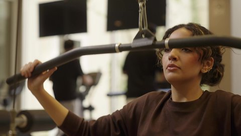 أنشطة بدنية للمحافظة على اللياقة والرشاقة، إيماءات السعادة والنشاط، اتباع أسلوب حياة صحي باستخدام الأجهزة التقنية، رياضات لتقوية العضلات ونحت الجسم، تصوير لشابة عربية خليجية سعودية ترتدي زي رياضي تقوم بممارسة التمارين الرياضية