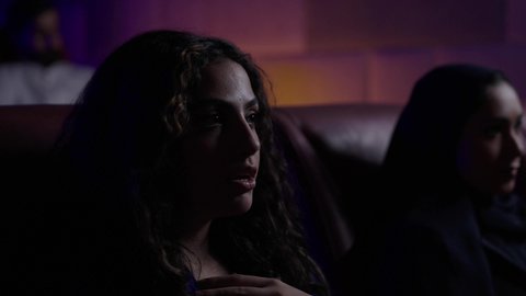 مشاهدة الأفلام المرعبه والعروض المسرحية في السينما، تعابير الخوف والذعر ،الاثارة والتشويق والاندماج ، قضاء أوقات ممتعة، فتاه عربيه خليجيه سعودية تجلس في صالة السينما
